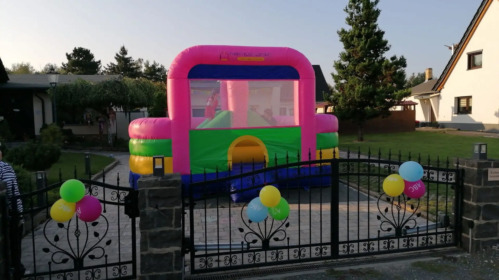 Lebendige Hüpfburg perfekt für Kinderfeste im Freien! Heller Hüpfburg mit transparenten Wänden für Kinder, im Garten aufgestellt.